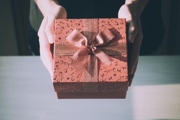 Person holding gift box wrapped with bow